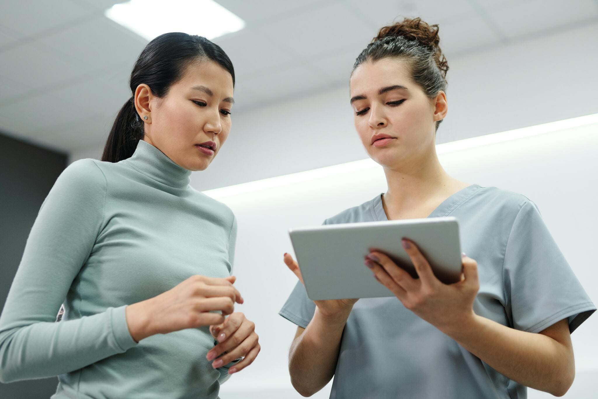 Junge Ärztin mit Tablet im Gespräch mit einer Patientin